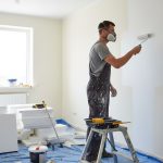 Un bricoleur peint un mur, illustrant les travaux DIY à la maison.