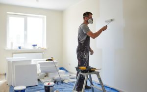 Un bricoleur peint un mur, illustrant les travaux DIY à la maison.