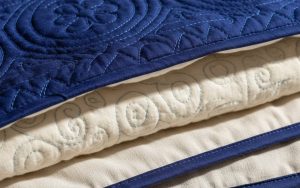Détail d'un tissu matelassé montrant ses couches et motifs de piqûre